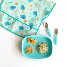 Load image into Gallery viewer, Bumkins Silicone Grip Tray: Blue with quinoa and veggies sits near an ocean-themed bib and blue utensils on a white background.