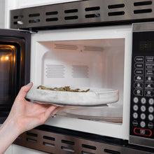 Load image into Gallery viewer, A hand places a Bumkins Silicone Grip Tray: Marble filled with food into an open microwave.
