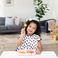 Load image into Gallery viewer, A curly-haired child holds a fork with a star-shaped piece of fruit, with snacks on a Bumkins Silicone Grip Tray: Pink on a white table.