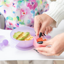 Load image into Gallery viewer, Hands attach a Bumkins Silicone Little Dipper Combo 2 Pack: Magenta Jelly filled with tomatoes to a purple bowl of food on a high chair tray.