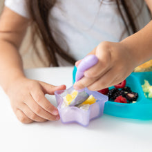 Load image into Gallery viewer, A child uses purple spoon for yogurt from a Bumkins Silicone Little Dipper Combo 2 Pack: Magenta Jelly next to a blue plate on a white table.