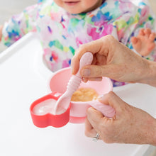 Load image into Gallery viewer, An adult uses spoon to feed a baby in a high chair from a red Bumkins Silicone Little Dipper 3-Pack: Tutti-Frutti.
