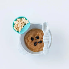 Load image into Gallery viewer, A bowl of applesauce sits on a white background, with a blue Bumkins Silicone Little Dipper Round 3-Pack: Gumdrop filled with cereal.
