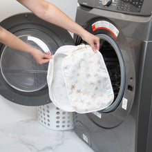 Load image into Gallery viewer, A person holds a Bumkins Packing Cube 2 Pack: Palm Daze in front of a front-loading washing machine.