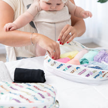 Load image into Gallery viewer, A person with a baby in a carrier organizes clothes in Bumkins Packing Cube 2 Pack: Mickey & Friends Varsity on a white bed.
