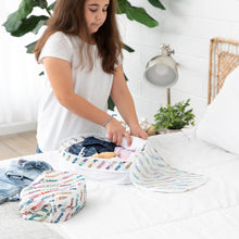 Load image into Gallery viewer, A girl uses Bumkins Packing Cube 2 Pack: Mickey & Friends Varsity to neatly pack clothes on a bed in a bright room.