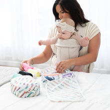 Load image into Gallery viewer, A mom with a baby in a carrier arranges clothes in a Bumkins Packing Cube 2 Pack: Mickey & Friends Varsity on a white bed.