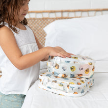 Load image into Gallery viewer, A child stacking Bumkins Packing Cube 2 Pack: Winnie + Friends on a bed with wicker headboard.