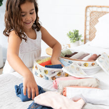 Load image into Gallery viewer, A girl organizing colorful clothes into Bumkins Packing Cube 2 Pack: Winnie + Friends on a bed.