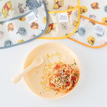Load image into Gallery viewer, Bumkins Silicone Plate + Spoon Set: Disney Winnie the Pooh, filled with pasta, is displayed next to bibs on a white background.
