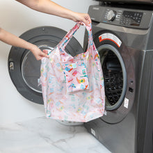 Load image into Gallery viewer, A person holds a Bumkins Packable Tote Bag: Boots in front of an open washing machine.