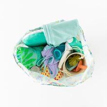 Load image into Gallery viewer, Top view of Bumkins Packable Tote Bag: Aloha Stitch on a white background, filled with swimming gear, featuring goggles, toys, and a towel.