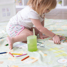 Load image into Gallery viewer, A girl on a patterned blanket reaches for a book, with colored pencils and a Bumkins Silicone Straw Cup with Lid: Sage close by.