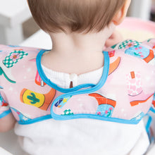 Load image into Gallery viewer, Close-up a child wearing a Bumkins Ruffle Apron Bib: Boots, with focus on the adjustable hook-and-loop closure.
