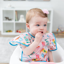 Load image into Gallery viewer, A girl wears Bumkins Ruffle Apron Bib: Boots in a high chair, looking curiously to the side as she places a snack in her mouth.