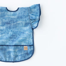 Load image into Gallery viewer, Bumkins Ruffle Apron Bib: Crushed Denim lays flat on a white background.