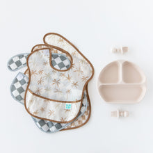 Load image into Gallery viewer, Bumkins SuperBib® 3 Pack: Palms + Check, made from waterproof fabric, next to a divided plate and utensils on a white background.