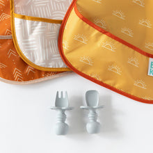 Load image into Gallery viewer, Close-up of Bumkins SuperBib® 3 Pack: Desert Boho arranged on a white background with gray baby utensils underneath.