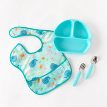Load image into Gallery viewer, A Bumkins SuperBib® 3 Pack: Rolling With the Waves lays flat on a white background beside a blue divided plate and blue utensils.