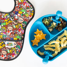 Load image into Gallery viewer, A Bumkins SuperBib® 3 Pack: Super Mario™ Power-Up lays next to a blue plate with cheese, pasta, fruit, and utensils on a white background.