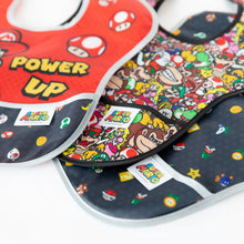 Load image into Gallery viewer, Close-up of Bumkins SuperBib® 3 Pack: Super Mario™ Power-Up fanned out on a white background, with focus on the front pocket.