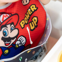 Load image into Gallery viewer, Close-up of a child wearing a red Bumkins SuperBib® 3 Pack: Super Mario™ Power-Up, with focus on yogurt dripping into the pocket.