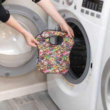 Load image into Gallery viewer, A person holds a A Bumkins SuperBib® 3 Pack: Super Mario™ Power-Up in front of an open front-loading washing machine.