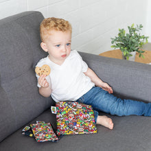 Load image into Gallery viewer, A curly-haired toddler on a gray couch holds a cookie beside Bumkins Reusable Snack Bag, 3-Pack: Super Mario™ Power Up.