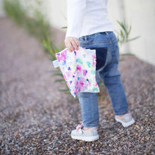 Load image into Gallery viewer, A child wearing jeans and sneakers walks on gravel, holding a Bumkins Reusable Snack Bag, Large 2-Pack: Watercolor & Brush Strokes.