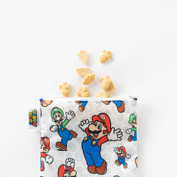 Bunny-shaped cookies spill from a Bumkins Reusable Snack Bag, Large: Super Mario™ & Luigi on a white background.