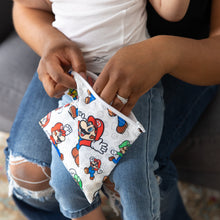 Load image into Gallery viewer, A person with a child on their lap reaches into a Bumkins Reusable Snack Bag, Large: Super Mario™ & Luigi.