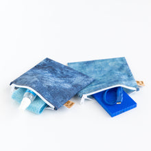 Load image into Gallery viewer, Roamio by Bumkins Reusable Snack Bag, Large 2 Pack: Denim on Denim lays open on a white background with camera cleaner & a charger inside.