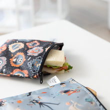 Load image into Gallery viewer, A Bumkins Reusable Snack Bag, Large 2 Pack: Everyday Is Halloween holds a sandwich on a white table.
