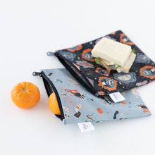 Load image into Gallery viewer, Bumkins Reusable Snack Bag, Large 2 Pack: Everyday Is Halloween sits on a white background with oranges and sandwiches.
