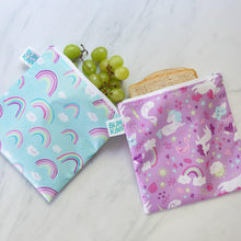 Load image into Gallery viewer, Bumkins Reusable Snack Bag, Large 2-Pack: Rainbows & Unicorns holds grapes and a sandwich on a marble surface.