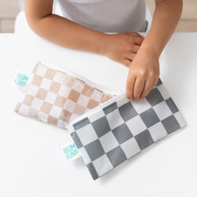 Load image into Gallery viewer, A child sits at a white table, holding Bumkins Reusable Snack Bag, Small 2 Pack: Double Check.