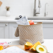 Load image into Gallery viewer, A Roamio by Bumkins Reusable Snack Bag, Small 2 Pack: Disco Boots sits in a lunch bag on a kitchen counter with fruit on a cutting board.