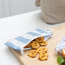 Load image into Gallery viewer, A Bumkins Reusable Snack Bag, Small 2 Pack: Coastal holds pretzels on a wood cutting board on a kitchen counter.