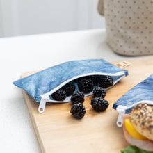 Load image into Gallery viewer, Blackberries spill from a Roamio by Bumkins Reusable Snack Bag, Small 2 Pack: Denim on Denim on a wood cutting board on a kitchen counter.