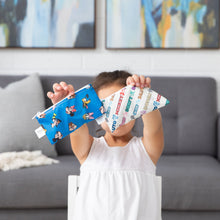 Load image into Gallery viewer, In a cozy living room, a child holds two Bumkins Reusable Snack Bag, Small 2 Pack: Mickey & Friends MVP in front of their face.