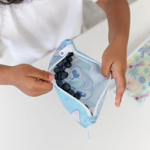 Load image into Gallery viewer, A child holds a Bumkins Reusable Snack Bag, Small 2 Pack: Stitch Star-ring Up Trouble with blueberries over a white table.