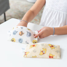 Load image into Gallery viewer, A child in a white dress reaches into Bumkins Bumkins Reusable Snack Bag, Small 2 Pack: Pooh Bear and Friends on a white table.