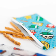 Load image into Gallery viewer, Close-up of pretzel sticks spilling from a blue Bumkins Reusable Snack Bag, Small 2-Pack: Super Mario™ on a white background.