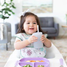 Load image into Gallery viewer, A toddler with a bow holds a Bumkins Silicone Straw Cup with Lid: Gray in a high chair next to a purple plate.