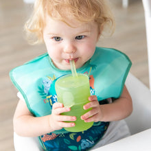 Load image into Gallery viewer, A toddler with blonde hair sips from a Bumkins Silicone Straw Cup with Lid: Sage, wearing a colorful bib with animal designs.