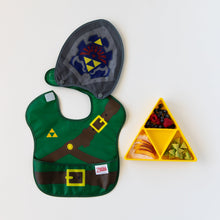 Load image into Gallery viewer, Bumkins Caped SuperBib®: The Legend of Zelda™ Link lays flat next to a yellow triangle-shaped plate with fruit on a white background.