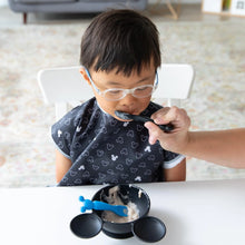 Load image into Gallery viewer, A child happily enjoys yogurt, being fed by an adult with a Bumkins Silicone Dipping Spoons: Mickey Mouse (Black and Blue) from a bowl.