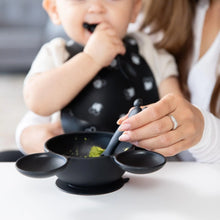 Load image into Gallery viewer, A baby in a black bib is fed green food with a Bumkins Silicone Dipping Spoons: Mickey Mouse (Classic Black) from a black bowl by an adult.