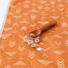 Load image into Gallery viewer, A Bumkins Silicone Dipping Spoons 3 Pack: Rocky Road rests among cereal pieces and milk splatter on an orange abstract printed mat.