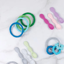 Load image into Gallery viewer, Bumkins Silicone Teething Rings 4 Pack: Summer lays near other teething toys and silicone spoons on a white marble background.